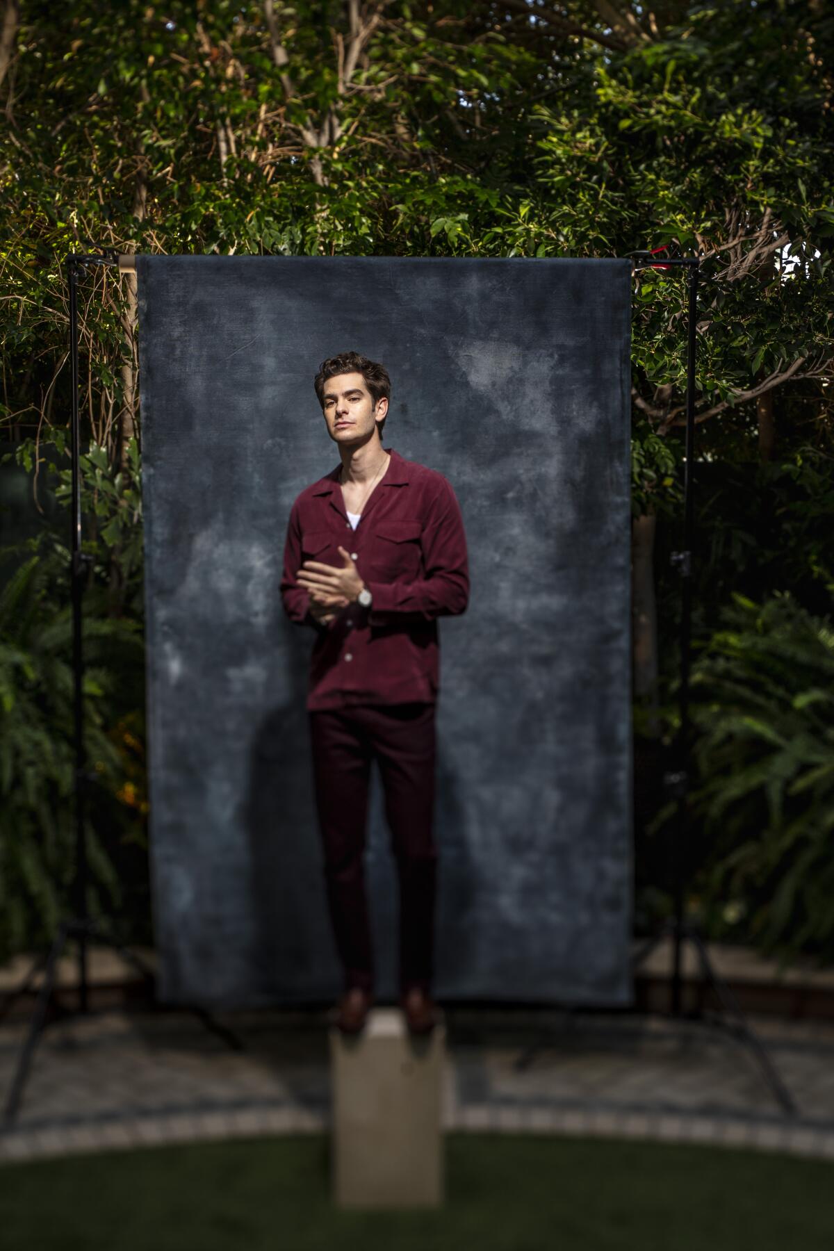 Andrew Garfield poses for a portrait in front of a gray backdrop.