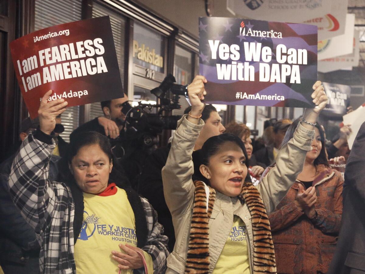 People cheer and hold up signs during a Feb. 17 town hall forum in Houston to help immigrants learn and prepare for programs under President Obama's immigration order.