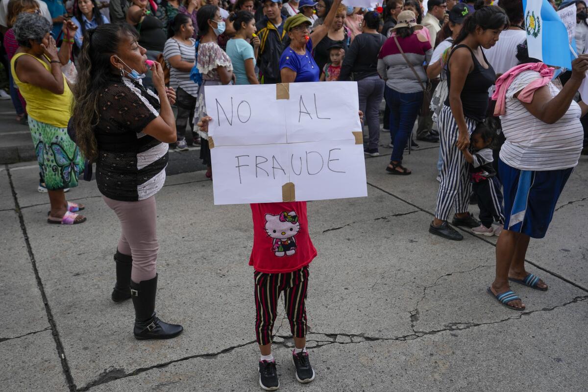 A child in Guatemala City holds a poster with a message that reads in Spanish: "No to fraud." 