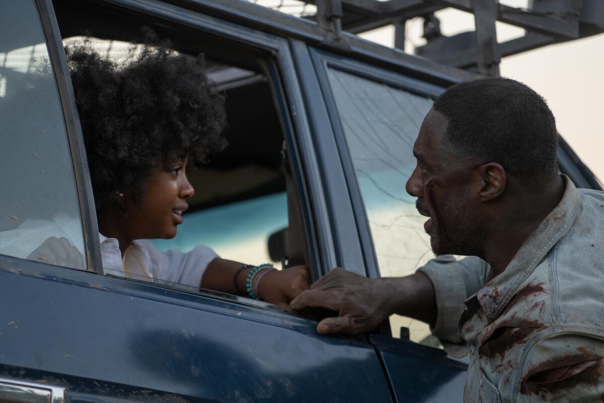 A father talks to his daughter through the passenger window of a car.