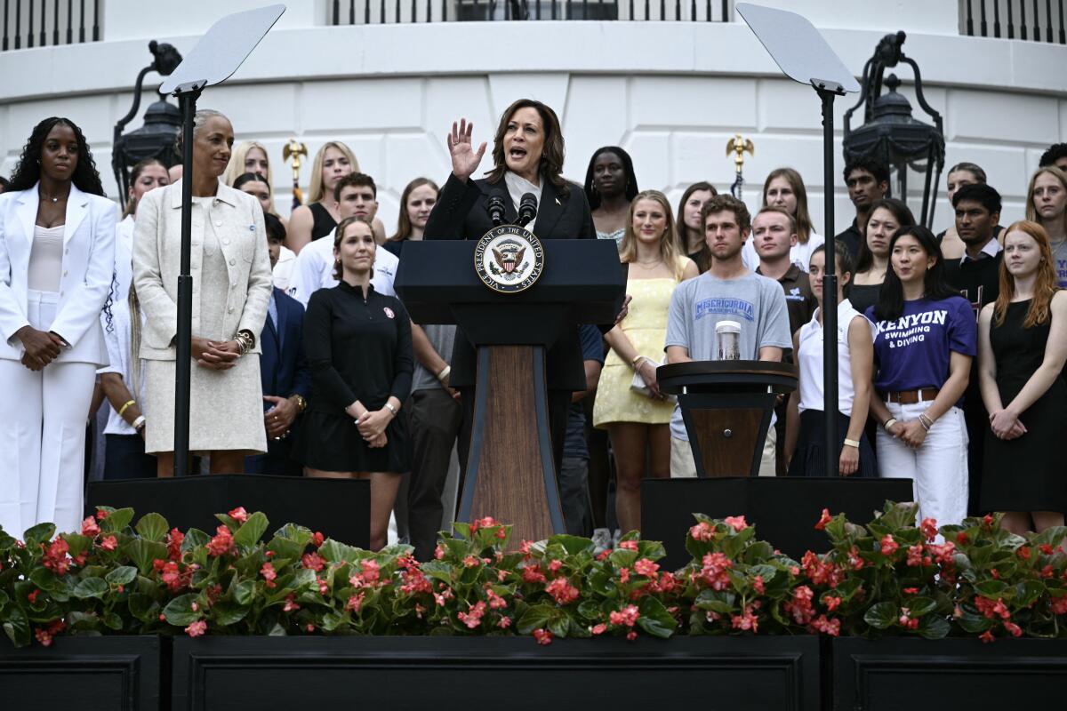 Vice President Kamala Harris at a lectern with young athletes.