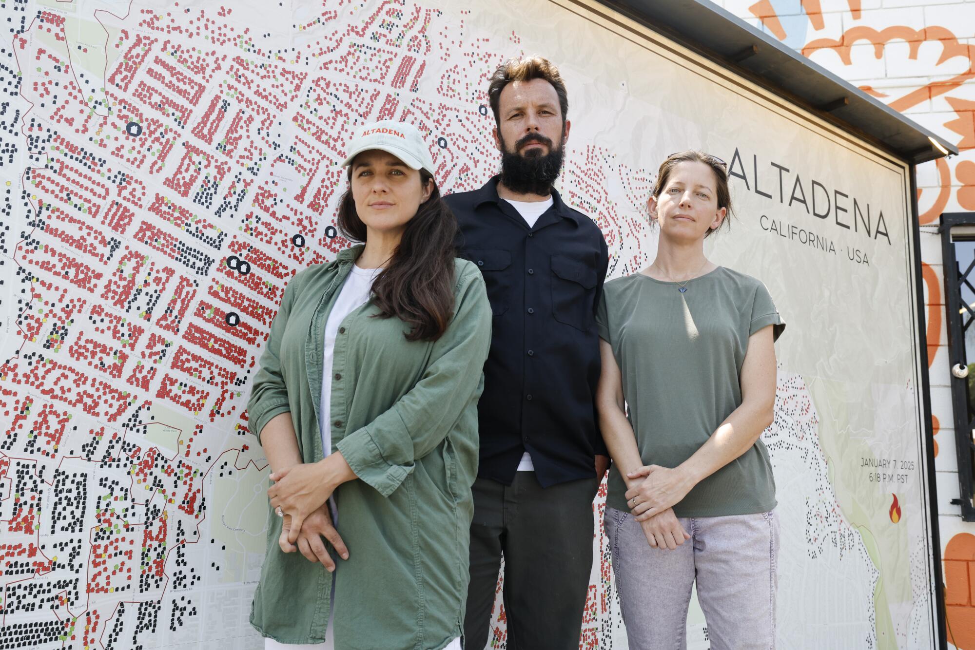 Three people stand in front of a big map.
