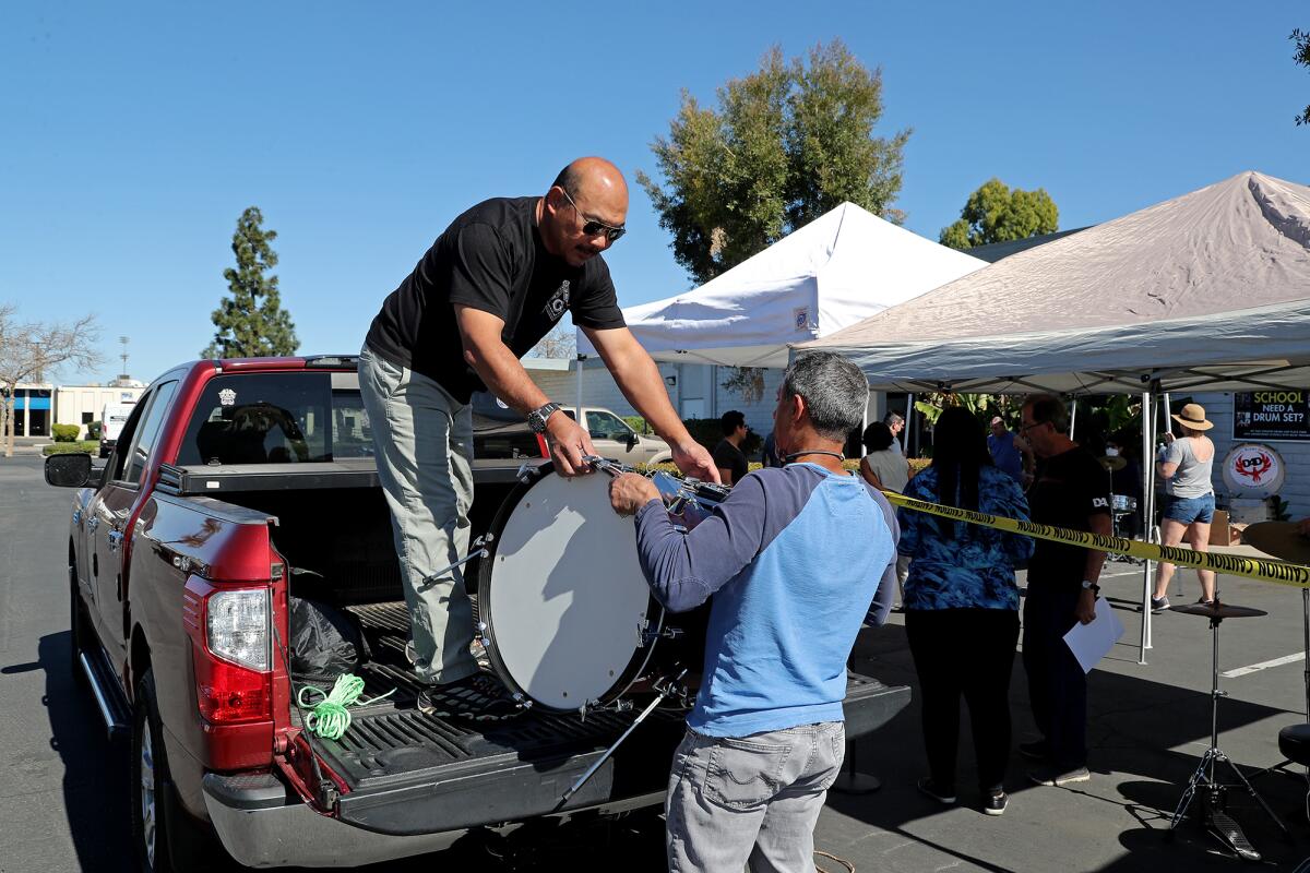 Mariel Teng, left, is helped by volunteer Wahid Shorter as he loads his truck with a donated drum set.