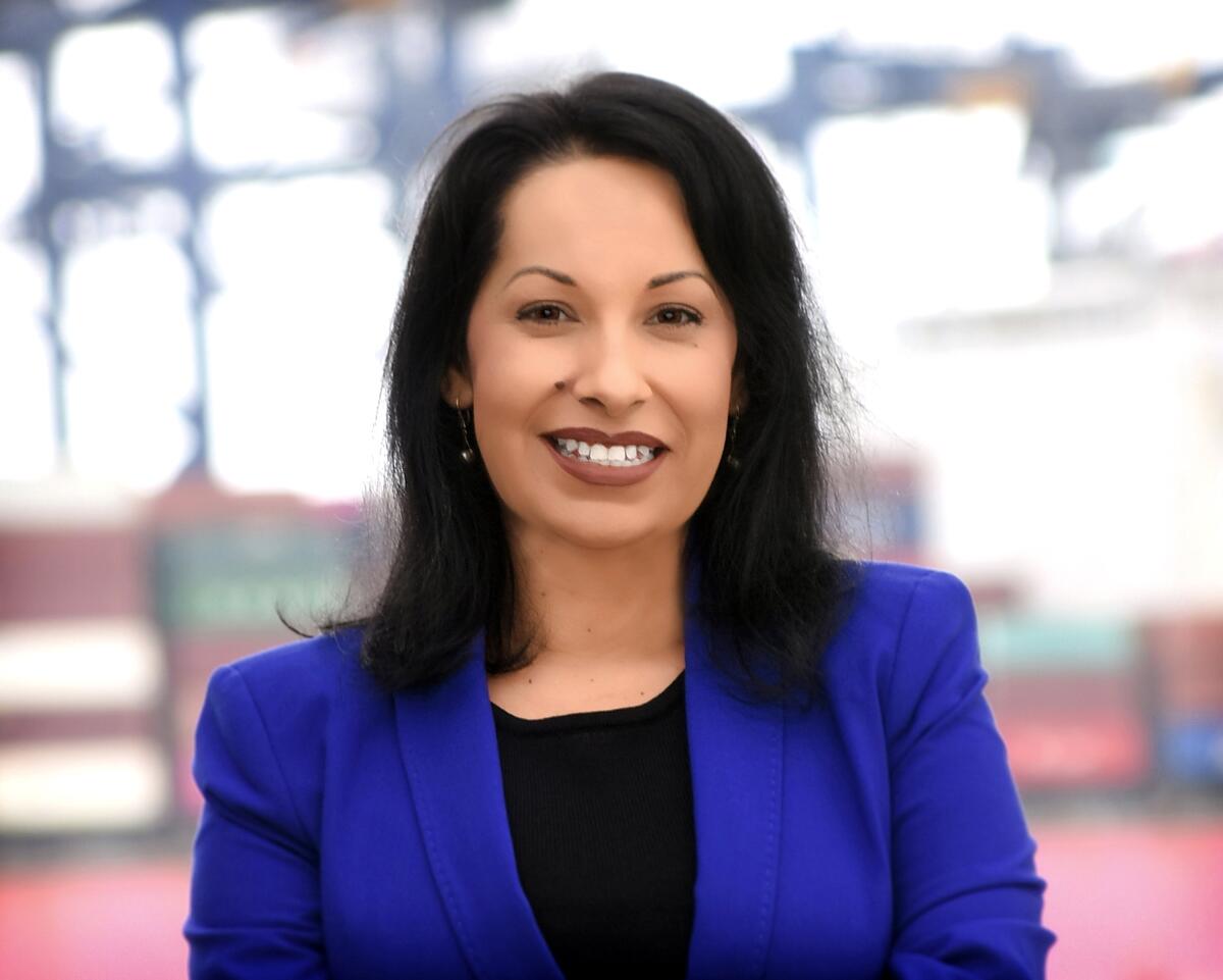 A woman with dark hair in a purple jacket and black top 