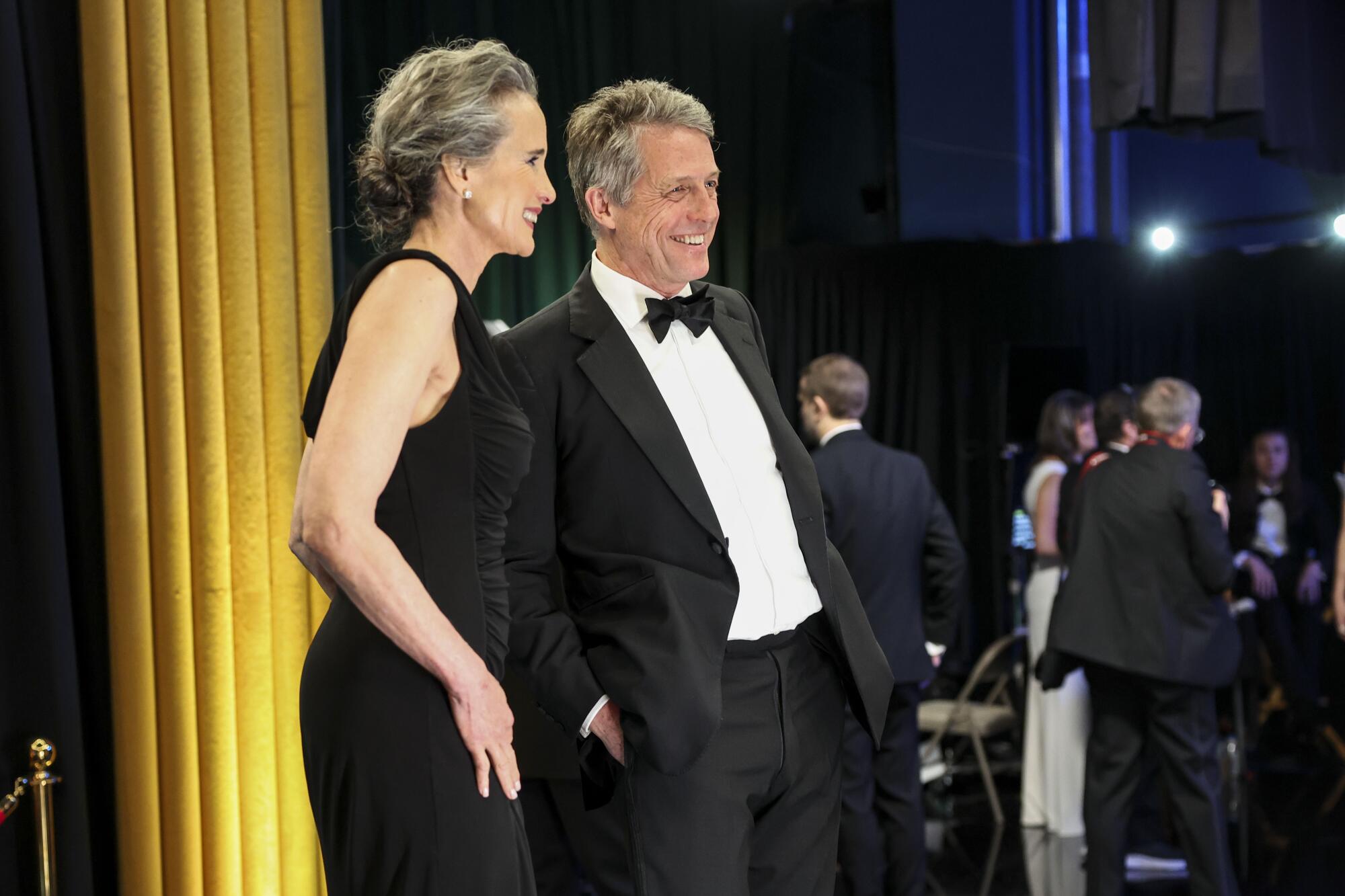 A smiling woman in a gown and a man in a tux backstage at the Oscars.