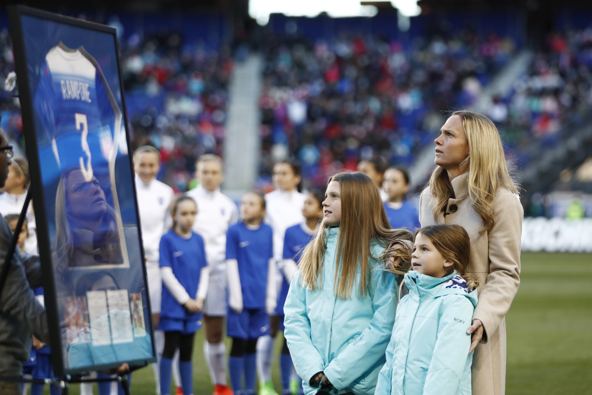 Former U.S. player Christie Rampone stands with her children during a 2017 ceremony honoring her 