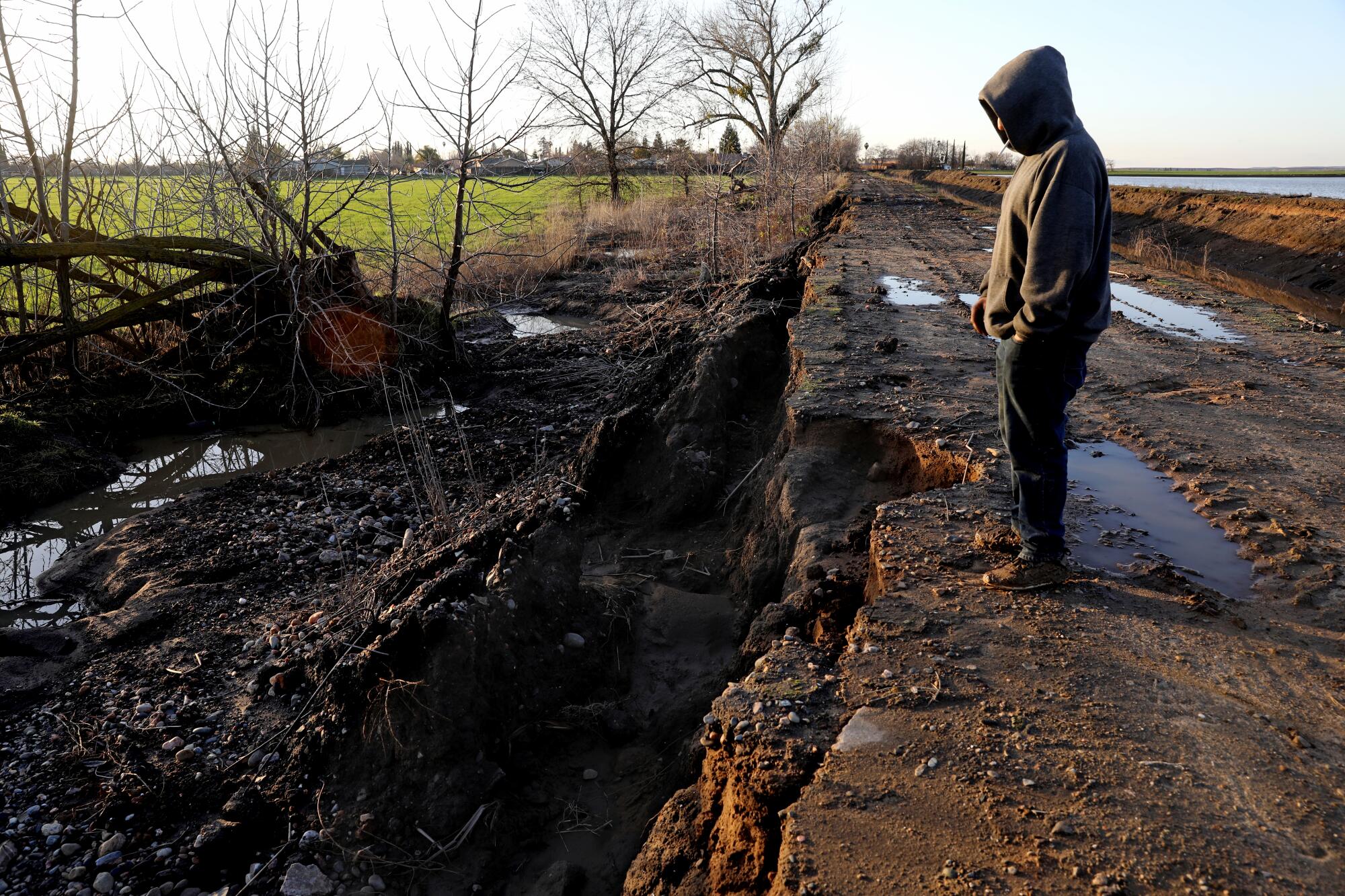 A man stands where storms caused the Planada Canal and Miles Creek to overflow and flood the town of Planada.