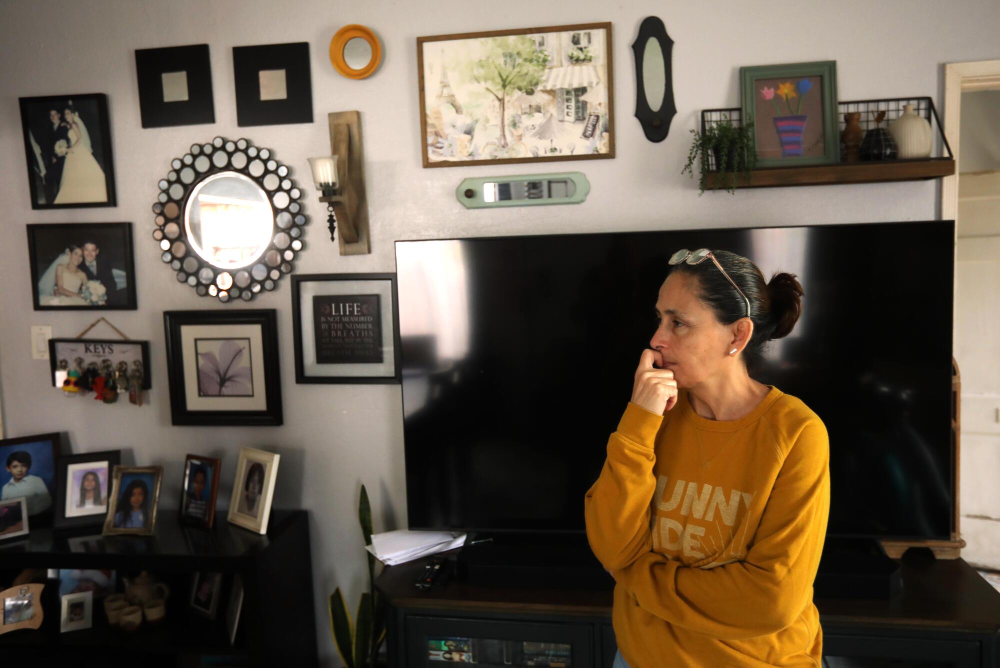 克劳迪娅·阿莱曼 (Claudia Aleman) 在她家的客厅里，墙上挂着照片。 