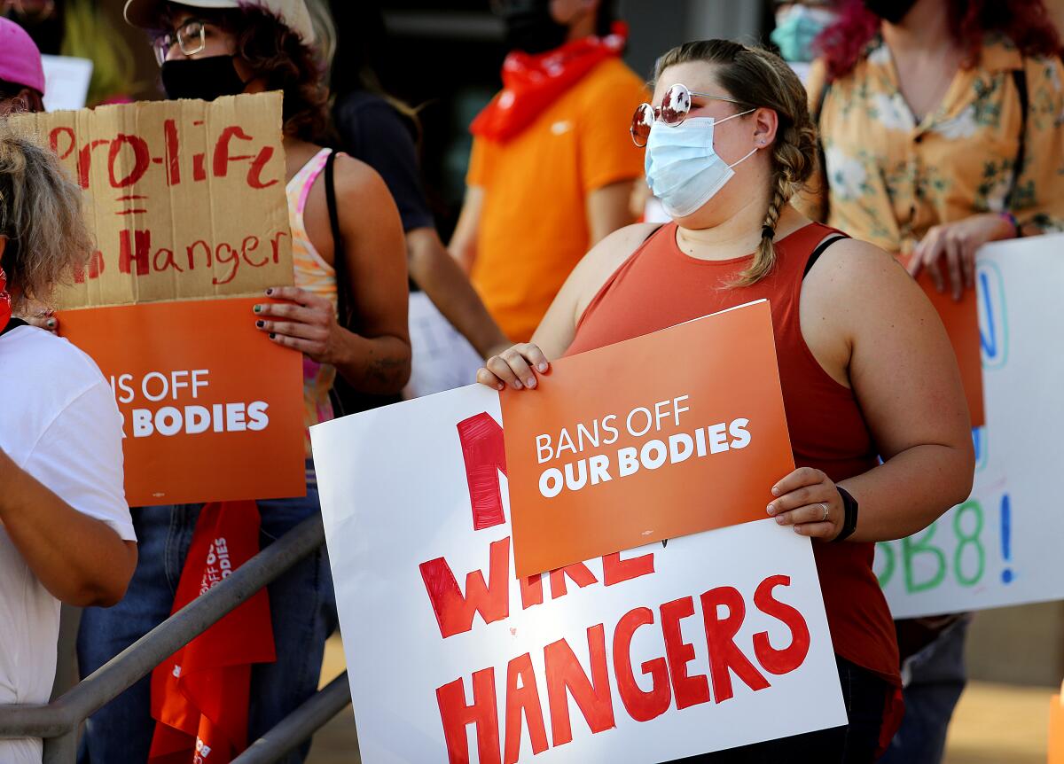 Abortion-rights supporters hold signs reading "Bans Off Our Bodies" and "No Wire Hangers."