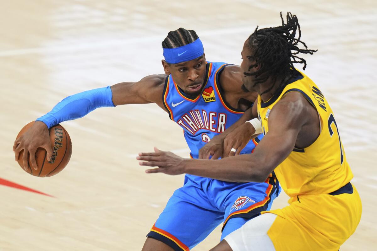 Oklahoma City guard Shai Gilgeous-Alexander controls the ball in front of Indiana forward Aaron Nesmith.