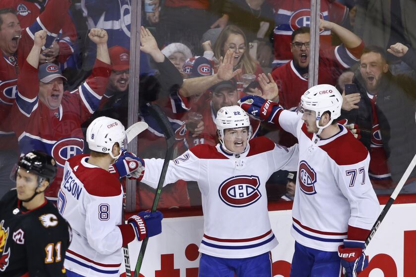 Montreal Canadiens' Cole Caufield, center, celebrates his goal against the Calgary Flames with Mike Matheson, left, and Kirby Dach during third period of an NHL hockey game in Calgary, Alberta, Thursday, Dec. 1, 2022. (Larry MacDougal/The Canadian Press via AP)