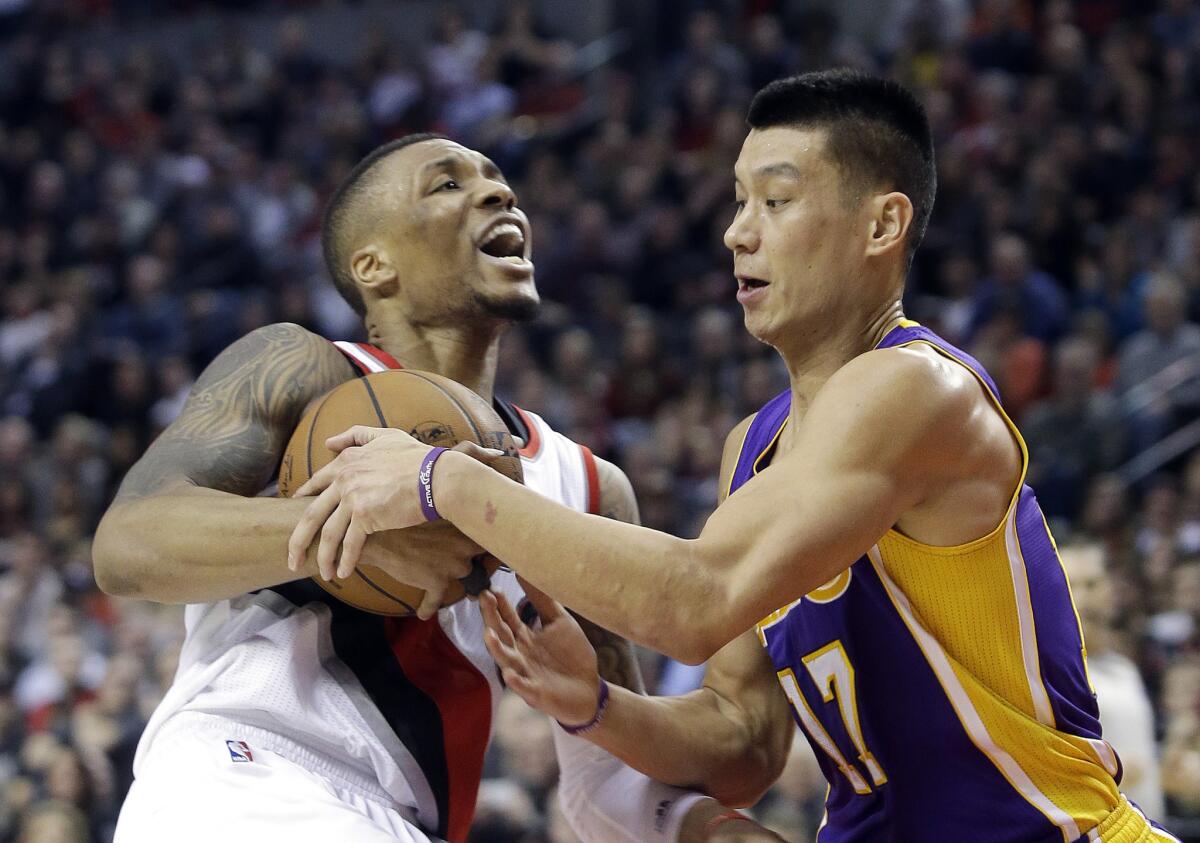 Lakers point guard Jeremy Lin tries to steal the ball from Trail Blazers point guard Damian Lillard.