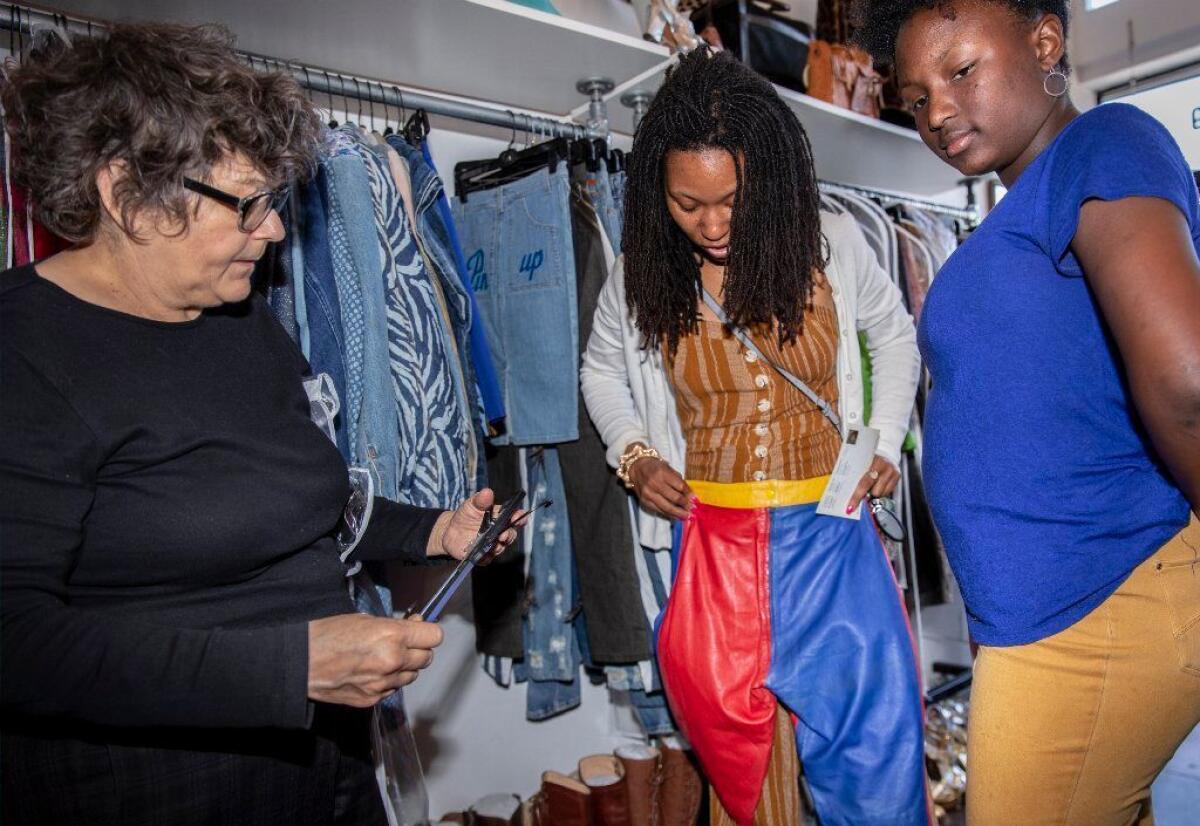 Webb helps Sarai Calvin, left, and her daughter, Zoi, pick out an outfit.