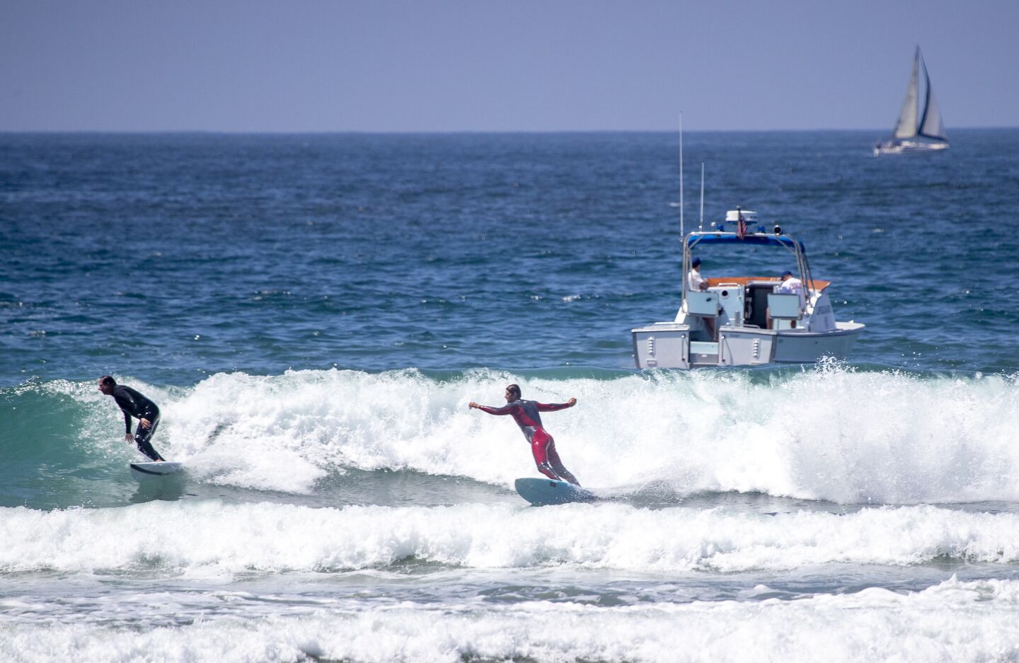Lifeguards patrol with a boat as surfers ride waves