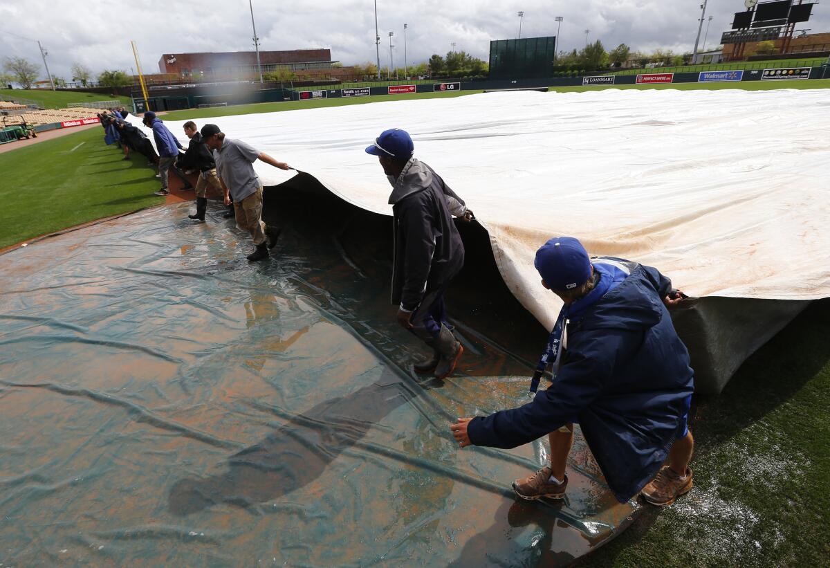 Camelback Ranch grounds crew remove the tarp from the playing field after the Chicago White Sox-Cleveland Indians exhibition baseball game was postponed due to rain in Glendale, Ariz., Saturday, March 1, 2014. (AP Photo/Paul Sancya) ** Usable by LA and DC Only **
