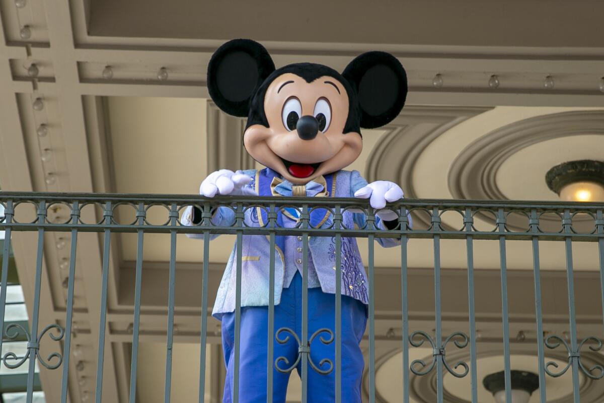 ARCHIVO - Un actor vestido como Mickey Mouse saluda a visitantes