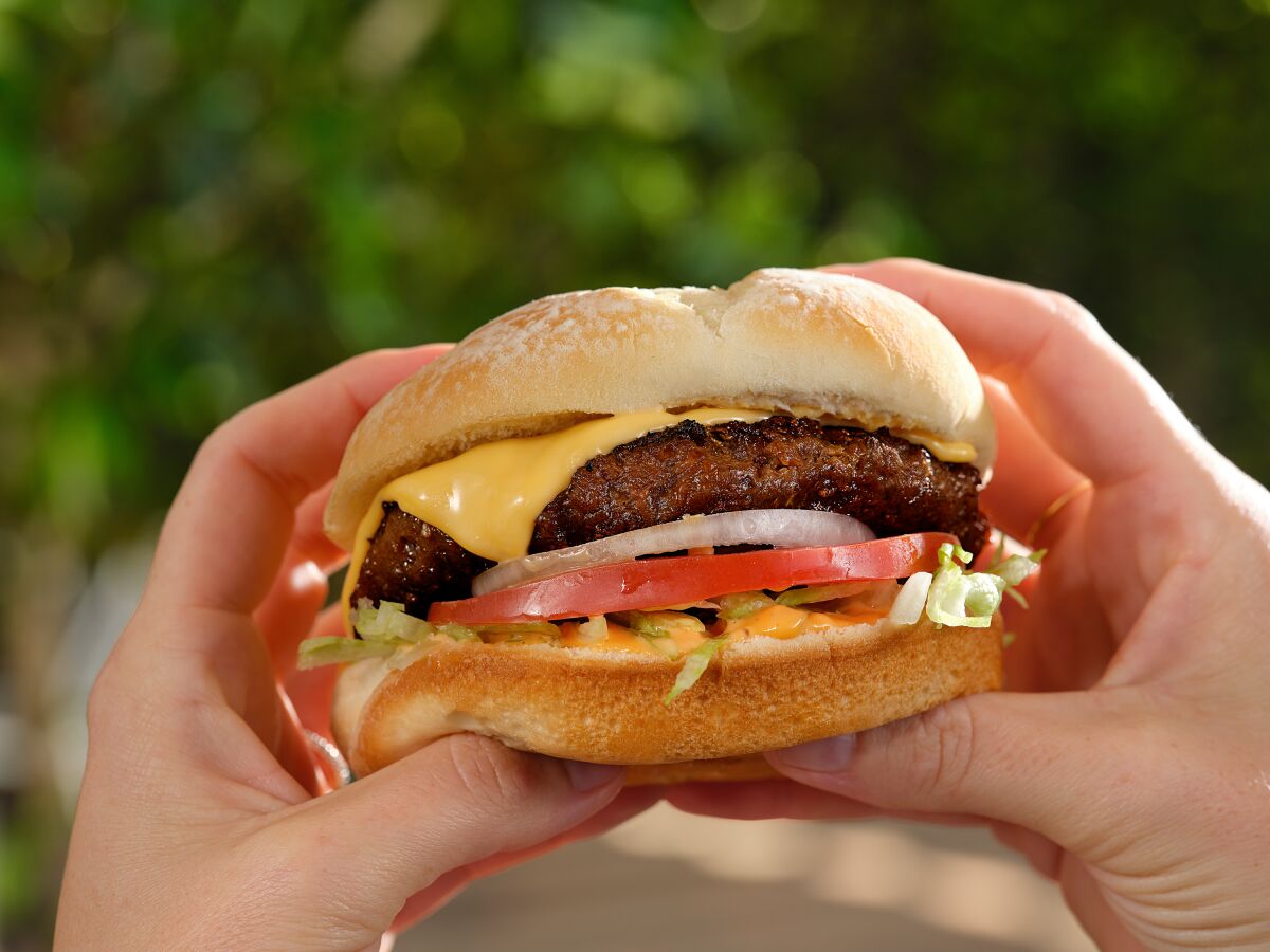 A pair of hands hold Beyond Meat's beyond burger.
