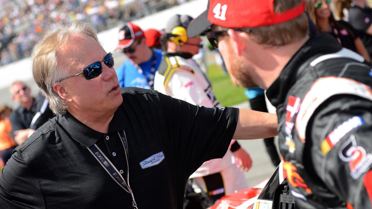 NASCAR team owner Gene Haas, left, speaks with driver Regan Smith before the start of the Daytona 500 on Feb. 22. Haas has seen plenty of triumph and tragedy with his drivers over the last year.