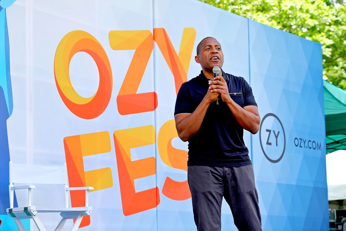 Ozy Media Chief Executive Carlos Watson speaks onstage in front of an Ozy Fest sign