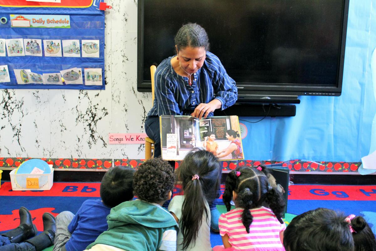 In this 2018 photo provided by Children's Aid, Nina Crews, illustrator of "A Girl Like Me," reads to children at an early childhood education center. Crews said the work of independent publishers and grassroots organizers are vital in bringing more racial diversity into children's books. (Adriana Alba/Children’s Aid via AP)