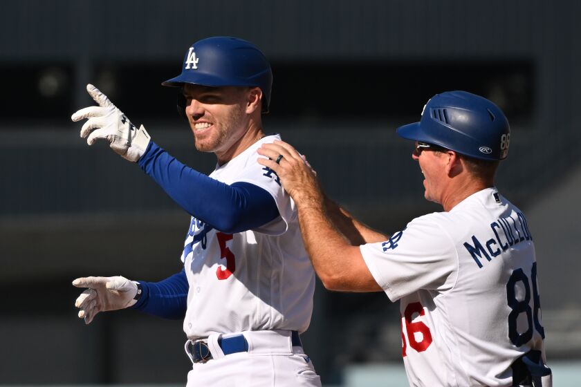 Los Angeles, California October 4 2022-Dodgers Freddie Freeman celebrates his RBI single with first base coach Clayton McCullough in the seventh inning against the Rockies at Dodger Stadium Wednesday. (Wally Skalij/Los Angeles Times)