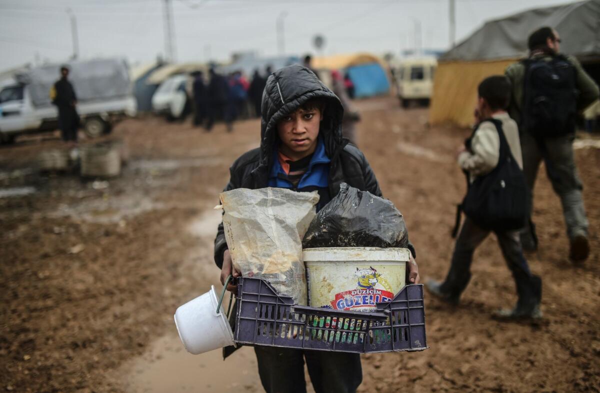 A child carries belongings as refugees from the Syrian city of Aleppo arrive at a Turkish border crossing gate on Feb. 6, 2016 .