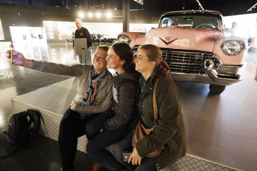 Visitors take a selfie in front of Elvis Presley's pink 1955 Cadillac Fleetwood on display at the Presley Motors Automobile Museum within the new Elvis Presley's Memphis complex in Memphis, Tenn.