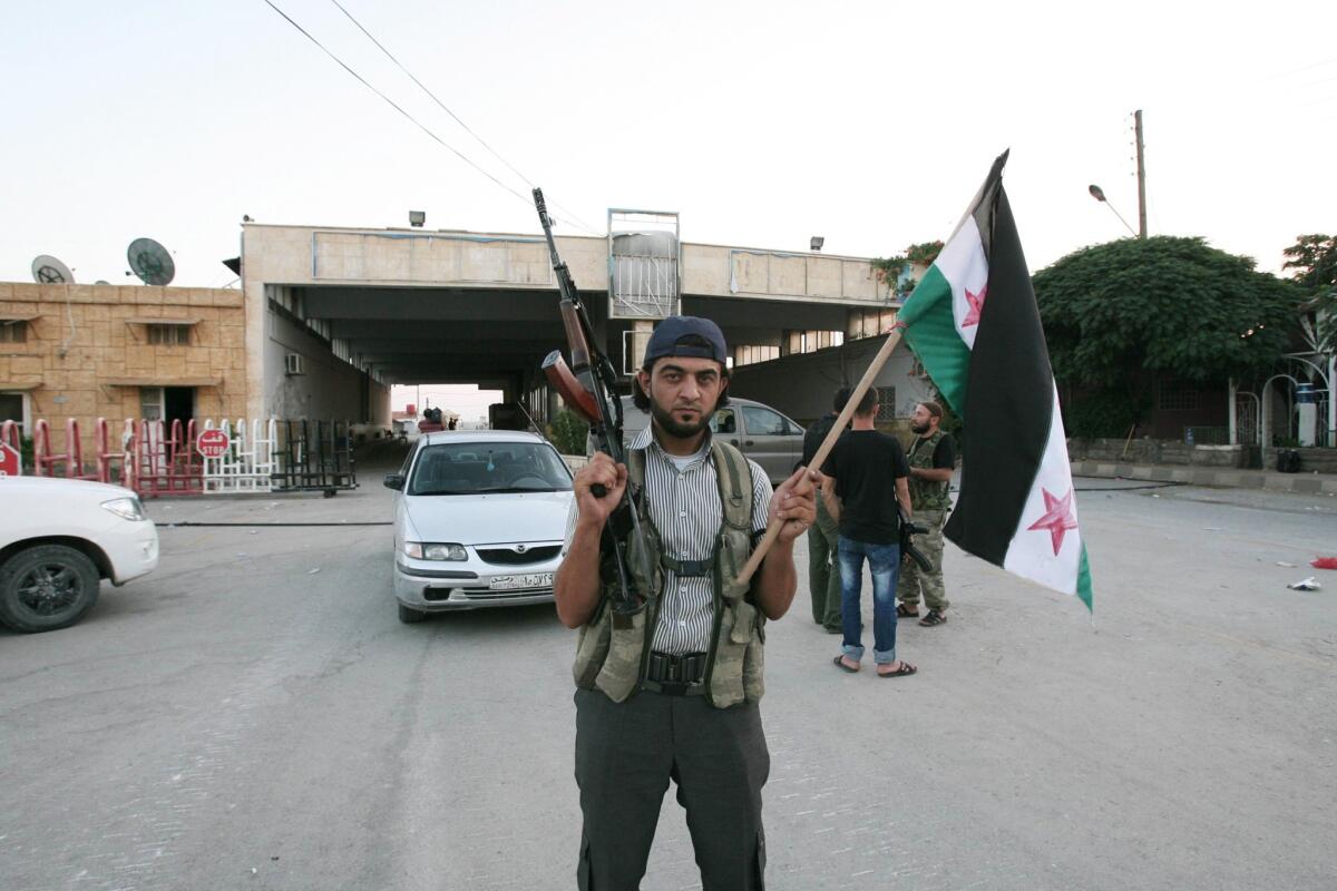 A rebel fighter is seen holding a rifle and a Syrian flag at the Bab al-Salameh border crossing into Turkey in July 2012. According to one opposition group, more than 40 people were killed in a bomb blast at the crossing Thursday.