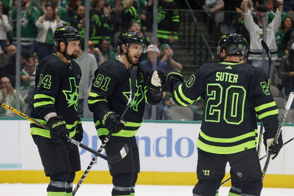 Dallas Stars center Tyler Seguin (91), is congratulated on his goal against the San Jose Sharks by left wing Jamie Benn (14) and defenseman Ryan Suter (20) during the first period of an NHL hockey game in Dallas, Saturday, April 16, 2022. (AP Photo/Michael Ainsworth)