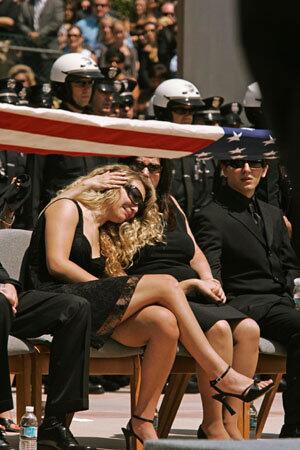 A Los Angeles Police Department color guard folds the U.S. flag Monday at a memorial service for LAPD Det. George Selleh. Barbara Selleh, his widow, hugs her daughter Jessica as son Scott Selleh looks on. Selleh was killed in an off-duty motorcycle accident last month.