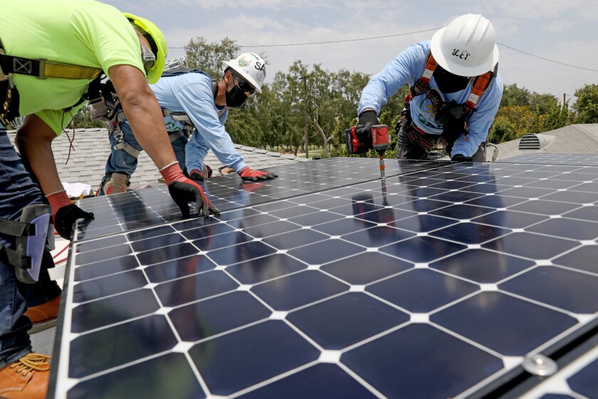 Workers install solar panels that will generate 5 kilowatts of energy in a home in Los Angeles.