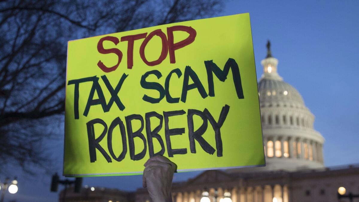 A rally participant holds a sign protesting a Republican-crafted tax cut plan outside the U.S. Capitol Building.