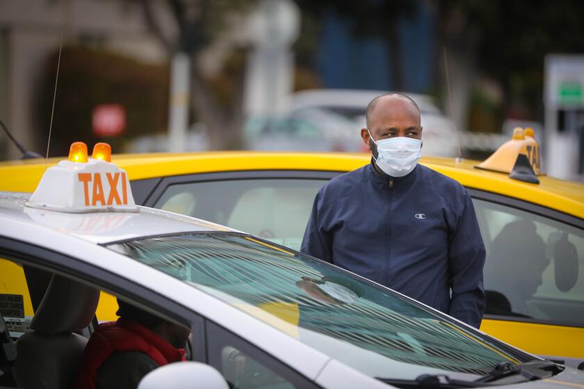 A taxi driver, (no id possible), wearing a protective mask, waits for passengers on the cruise ship Disney Wonder, docked at the B Street Pier on Embarcadero, Thursday morning, March 19, 2020 in San Diego, California, to disembark. After the passengers leave the ship, it will then depart with only the crew onboard. There were no known cases of the coronavirus. The ship departed New Orleans on a 15-day cruise, March 6, before many of the measures taken across the country to aggressively target the spread of coronavirus were in place.