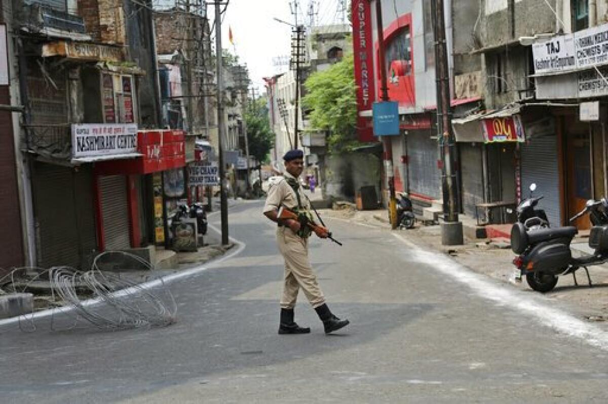 An Indian paramilitary soldier stands guard near closed shops in Jammu, in India's Kashmir region.  India has cracked down on the  region, revoking its quasi-autonomous status.