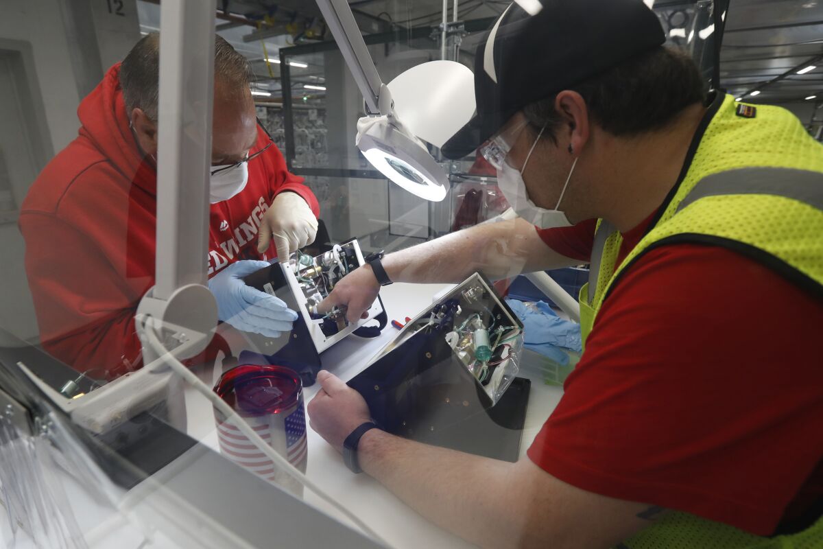 FILE - In this Wednesday, May 13, 2020 file photo, Ford Motor Co. employees work a ventilator at the Rawsonville plant in Ypsilanti Township, Mich. The plant was converted into a ventilator factory, as hospitals battling the coronavirus report shortages of the life-saving devices. According to the Institute for Supply Management, U.S. manufacturing rebounded in June 2020 as major parts of the country opened back up, ending three months of contraction in the sector caused by the coronavirus pandemic. (AP Photo/Carlos Osorio)