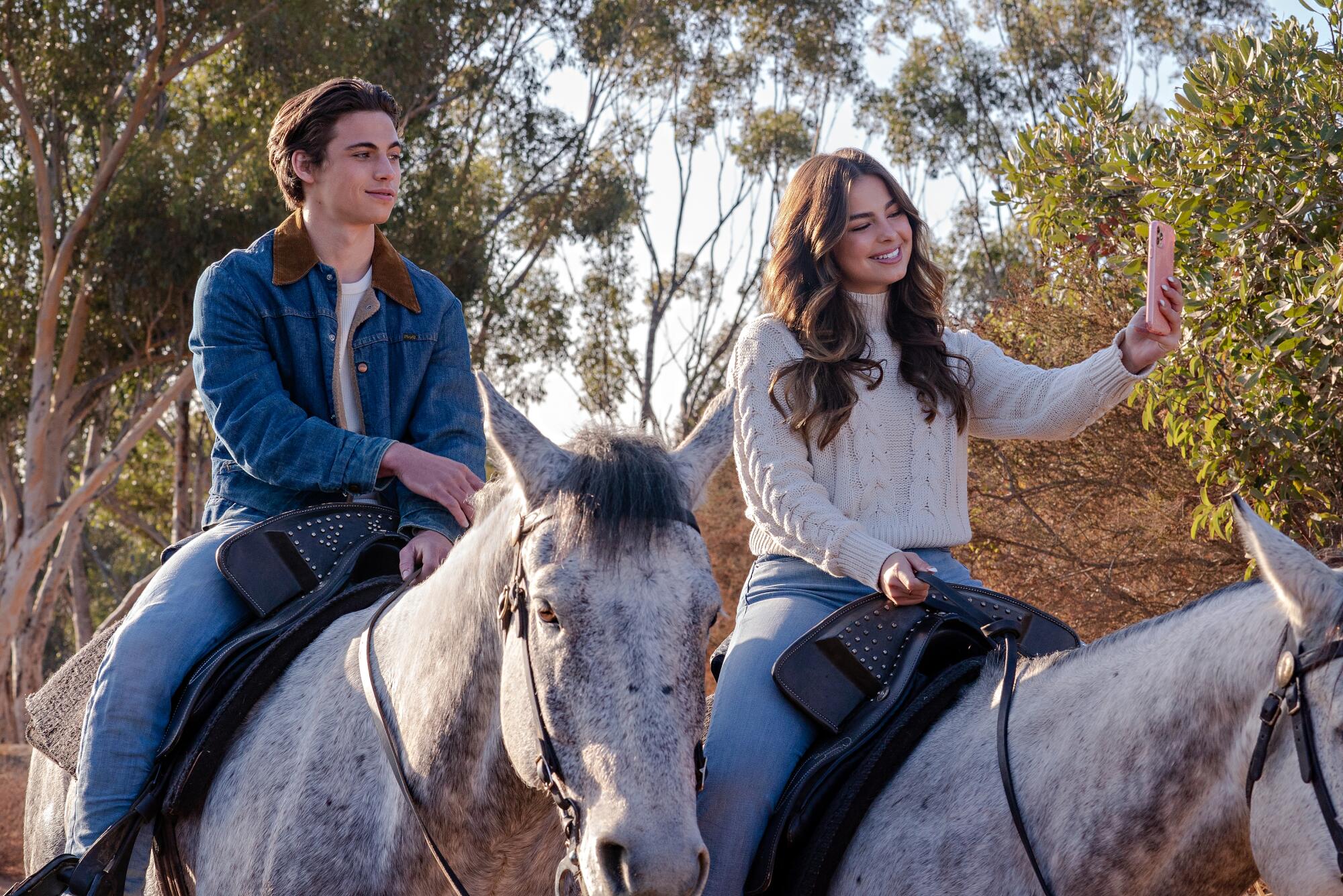 A girl takes a selfie of her and her male love interest while on horseback 