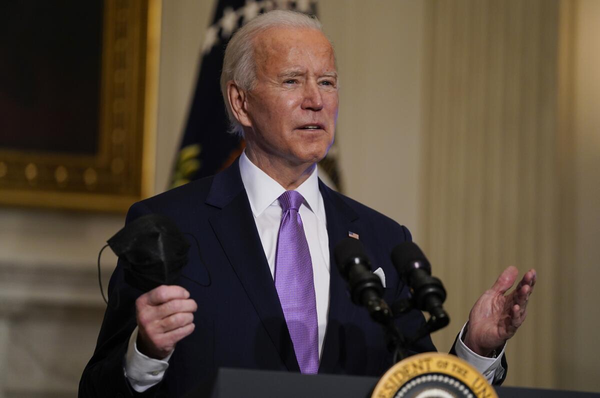 President Biden holds his face mask as he delivers remarks on COVID-19 at the White House. 