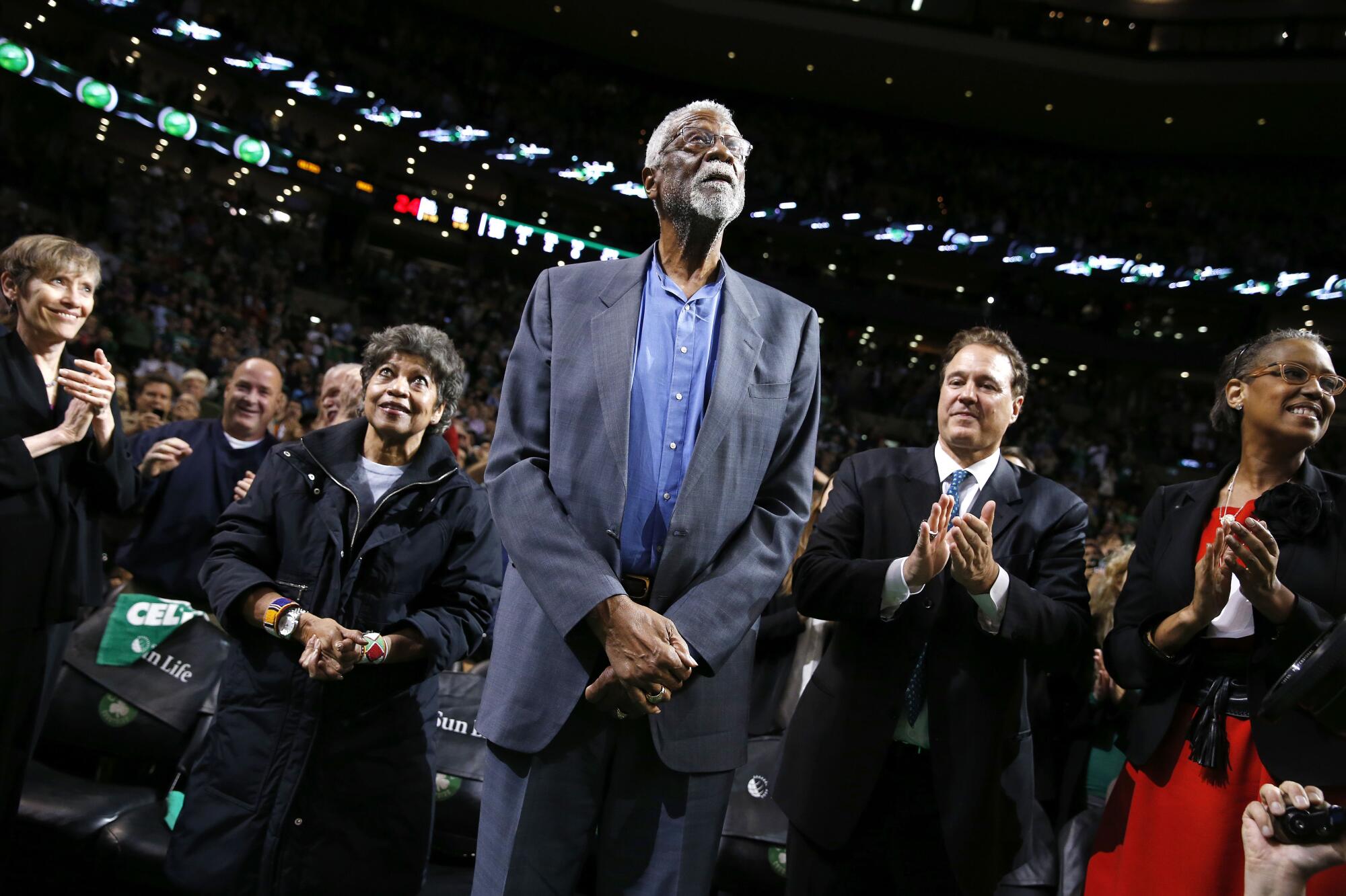 Bill Russell looks up as the people flanking him applaud.