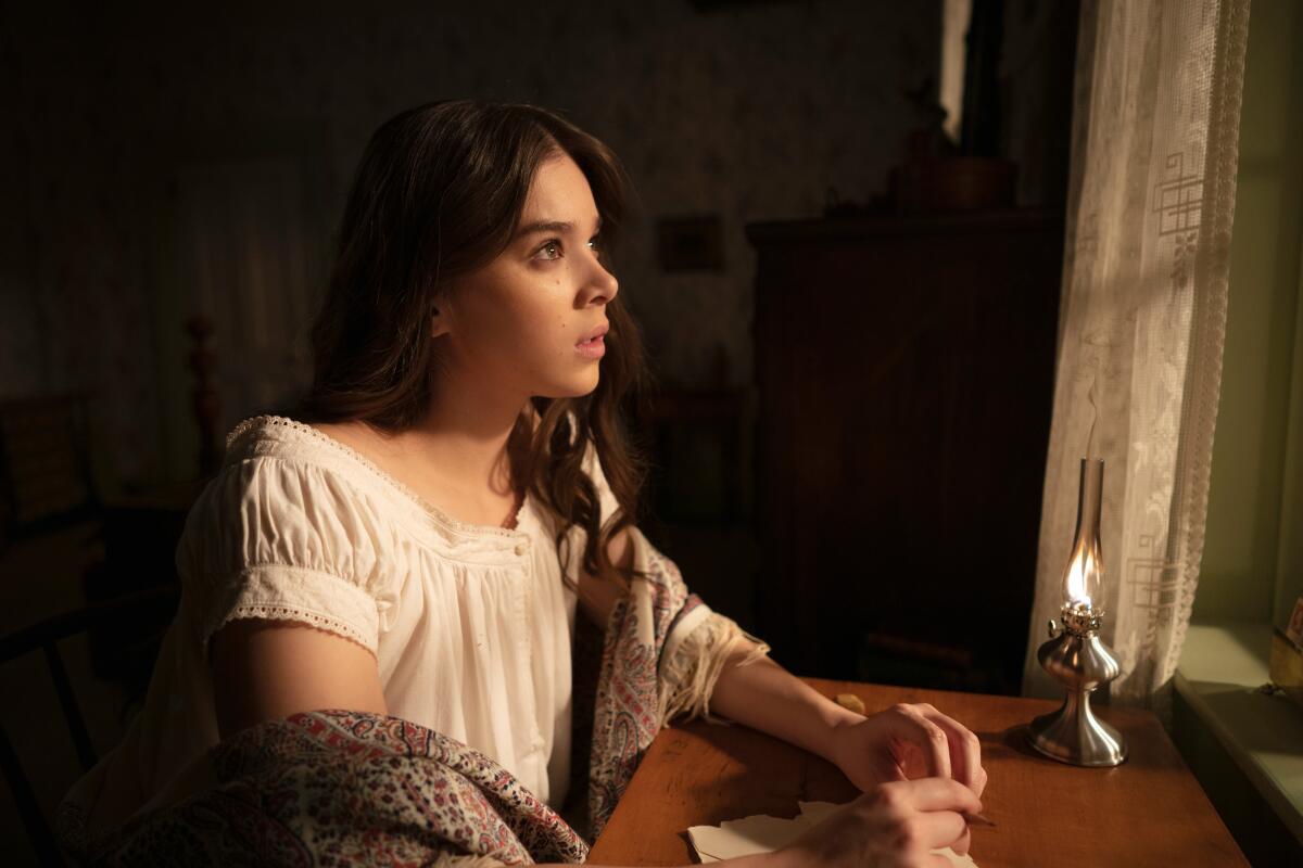 Hailee Steinfeld sits at a desk and looks out a window in "Dickinson."