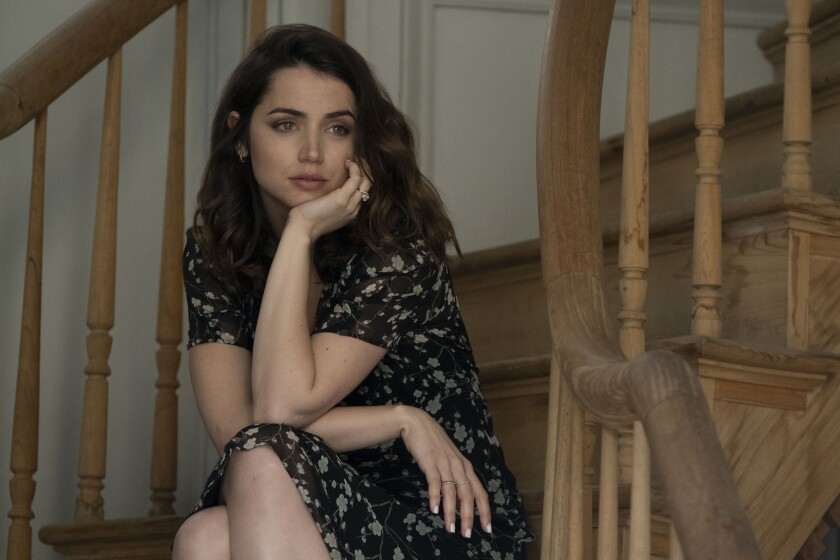 A woman sits on a staircase with her hand under her chin.