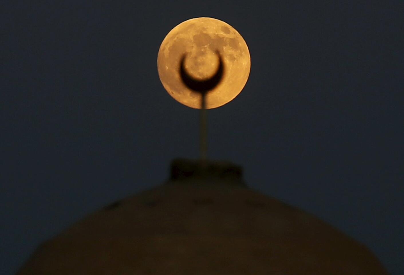 A supermoon, the last of this year's supermoons, rises over a minaret of a mosque in Wadi El-Rayan Lake at the desert of Al Fayoum Governorate, south west of Cairo, Egypt.