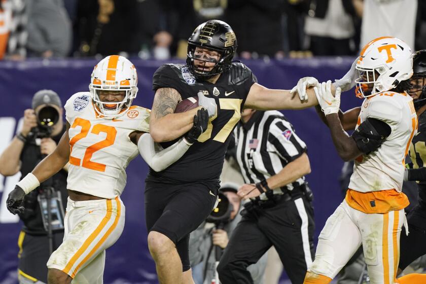 Purdue tight end Payne Durham (87) fends off Tennessee defenders Jaylen McCollough (22) and Kamal Hadden, right, in the second half of the Music City Bowl NCAA college football game Thursday, Dec. 30, 2021, in Nashville, Tenn. (AP Photo/Mark Humphrey)