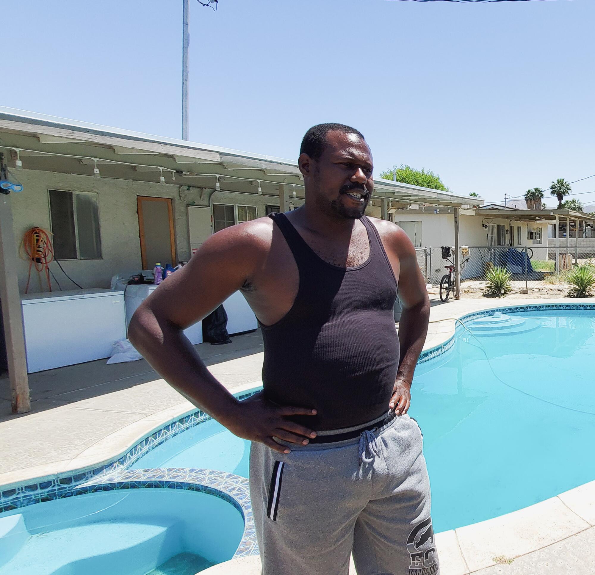 A man standing next to a backyard swimming pool