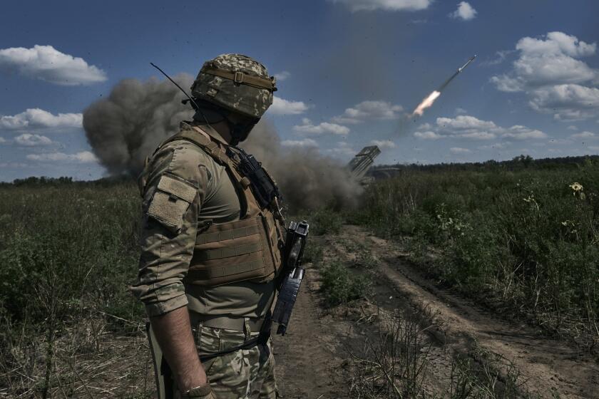 A Ukrainian soldier watches a Grad multiple launch rocket system firing shells with flyers near Bakhmut, Donetsk region, Ukraine, Sunday, Aug. 13, 2023. (AP Photo/Libkos)