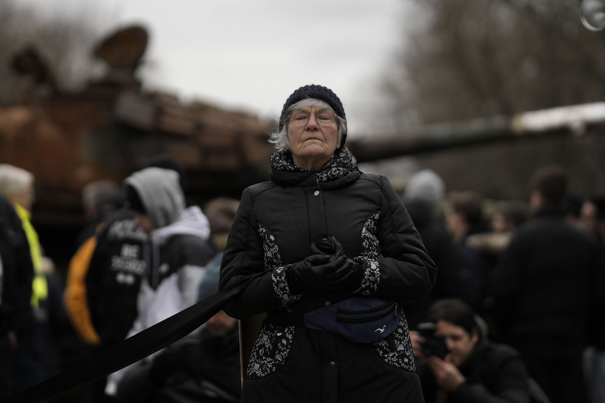 A woman attending a so called 'funeral march' stands in front of the wreckage of a Russian T-72 tank