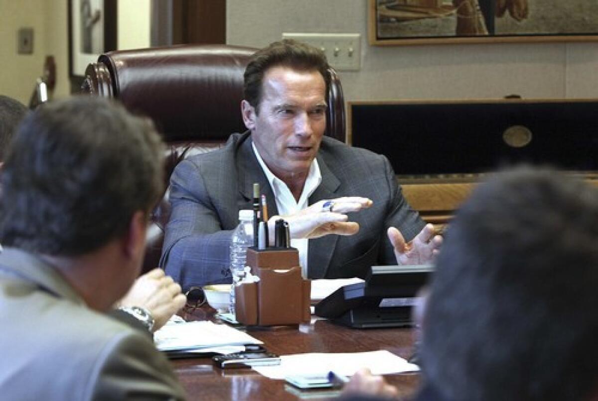 Gov. Arnold Schwarzenegger talks with his staff Monday about potential line-item vetoes while going over the revised state budget. Hes expected to sign the budget package today.