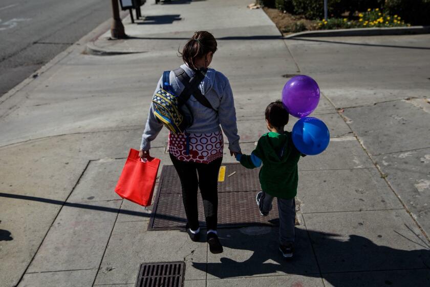 A Salvadoran immigrant who is in the U.S. illegally walks with her son, 5, and daughter (not visible in a carrier) after paying gas and power bills. “I haven’t been out in almost a week,” she said. “I’ve been afraid."