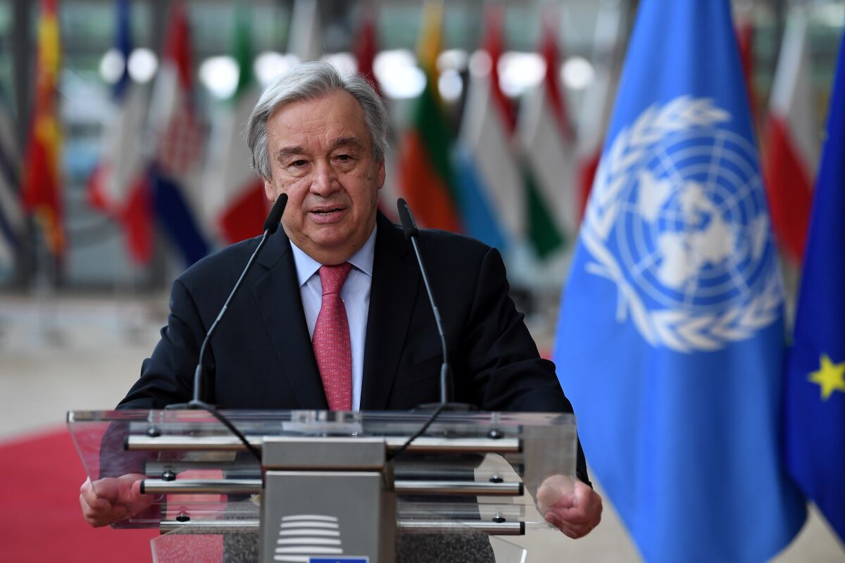 António Guterres stands at a lectern with a blue and white flag next to him