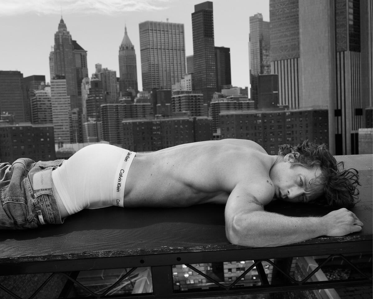 Jeremy Allen White lies on a rooftop with his jeans pulled down past his butt. 