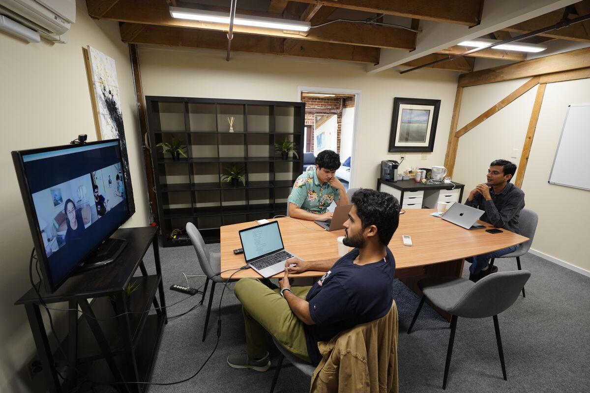 RunX CEO Ankur Dahiya, center, takes part in a video meeting with employees JD Palomino, top left, and Nitin Aggarwal, right, at a rented office in San Francisco, Friday, Aug. 27, 2021. Technology companies like RunX that led the charge into remote work early as the pandemic unfurled, are confronting a new challenge as it winds down: how, when and even whether they should bring their long-isolated employees back to offices that have been designed for teamwork. (AP Photo/Eric Risberg)